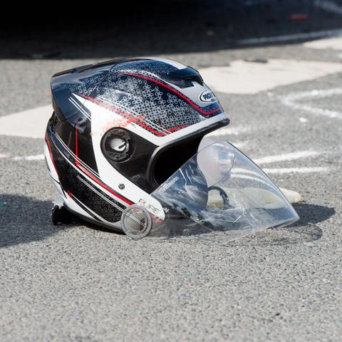 Ein beschädigter Helm liegt nach einem schweren Motorradunfall auf einer Straße  (Foto: dpa Bildfunk, picture alliance / dpa | Julian Stratenschulte)